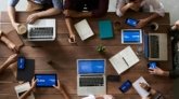 Overhead view of a diverse team in a business meeting using laptops and tablets.