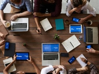 Overhead view of a diverse team in a business meeting using laptops and tablets.